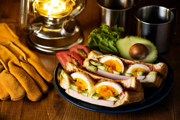 木製のテーブルにホットサンドとコーヒーとランタンの夜のキャンプ飯