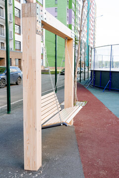 A wooden swing hangs on a log, a children's playground, a place to relax in the city.