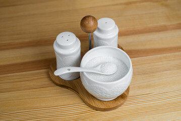 A kitchen set that includes sugar, pepper and salt with a spoon