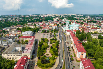 Fototapeta na wymiar aerial panoramic view from great height on red roofs of old big city with skyscrapers and white fluffy clouds