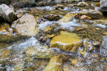 Close-up of mountain water with stones in the river.