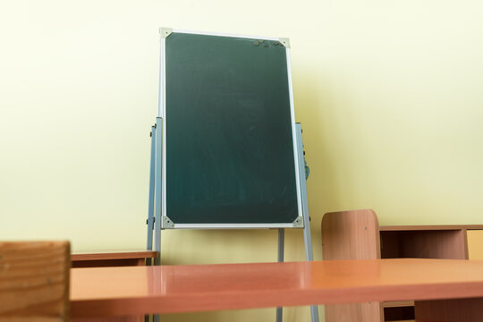 Empty dark green vertical chalkboard stands in empty classroom. Education concept.