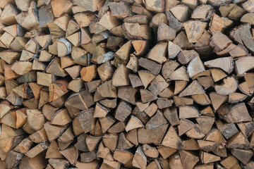 Large stack of raw firewoods material folded outdoor. Birch and oak chopped logs background.