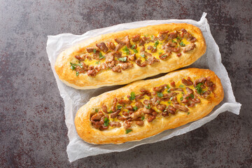 Pastrmalija is a Macedonian bread pie made from dough and meat is usually oval-shaped with sliced meat cubes on top of it closeup on the parchment on the table. Horizontal top view from above