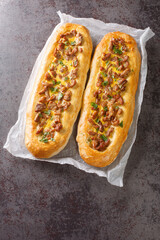 Open meat pie with egg, stuffed bread, pizza close-up on parchment on the table. Vertical top view from above