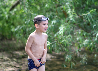 the boy is standing on the shore in underwater glasses © Елена Ланцова