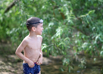 the boy is standing on the shore in underwater glasses
