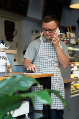Young caucasian waiter with down syndrome using phone and digital tablet