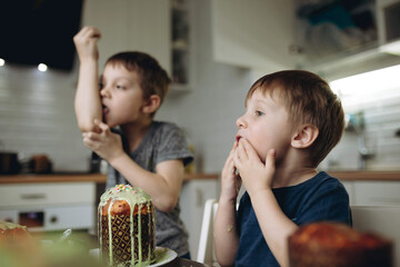 Brothers decorating Easter cakes with glace icing eating sugar topping. Image with selective focus