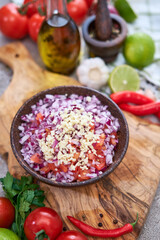making salsa dip sauce - chopped garlic, tomatoes and onion in wooden bowl