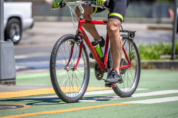 Obraz premium Stylish male athlete cyclist exercising cycling on a bike path with crossroad in urban city