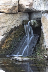 A closeup of a water fall in Carey Park in Hutchinson Kansas USA with limestone rocks that's bright and colorful.