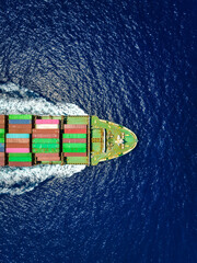 Aerial top view of a loaded cargo container ship travelling over the sea