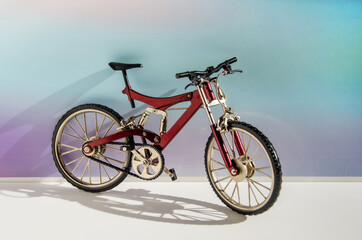 Realistic model of a toy metal full-suspension mountain bike. Miniature bicycle on a colored background with text space.