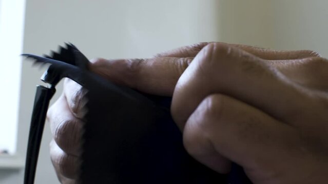 An extreme close up shot of the hands of an Asian Indian man cleaning the lenses of his spectacles with a microfiber cloth