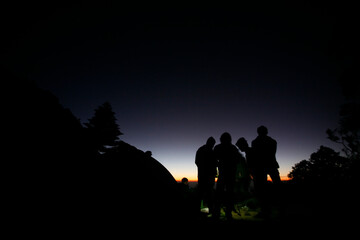 Hikers or tourists stands on mountain top at sunset