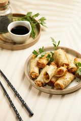 Traditional southeast asian starter dish spring or summer rolls - deep fried dim sum dumplings stuffed with vegetables with soy sauce, fresh coriander on grey plate with black chop sticks