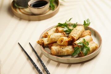 Traditional southeast asian starter dish spring or summer rolls - deep fried dim sum dumplings stuffed with vegetables with soy sauce, fresh coriander on grey plate with black chop sticks, top view
