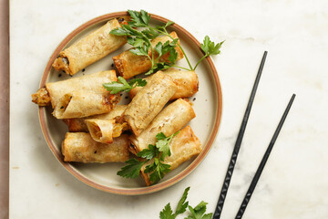 Traditional southeast asian starter dish spring or summer rolls - deep fried dim sum dumplings stuffed with vegetables with soy sauce, fresh coriander on grey plate with black chop sticks, top view