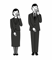 涙を拭く喪服の男女