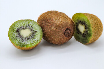a kiwi fruit cut in half plus another whole on white background