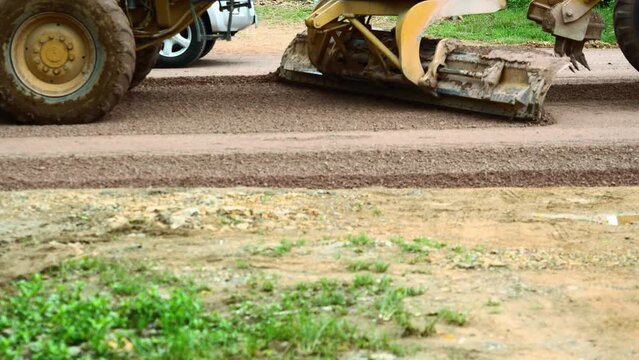 Machines are grading  dirt land in road construction,  Motor Grader or Blade Grading is driving  at construction site level the ground and gravel stone