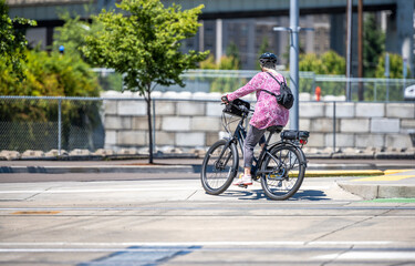 Fototapeta na wymiar Woman with a backpack takes care of her health and exercises cycling while riding on a bike path