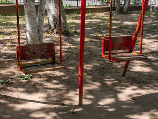 Fototapeta na wymiar Children's swing in a public park on a sunny summer day.