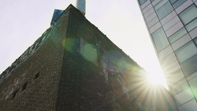 Sun flares between a brick building and an office tower in New York