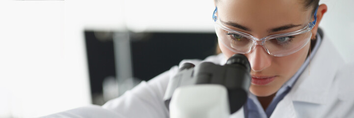 Female chemist investigate sample under microscope equipment in lab