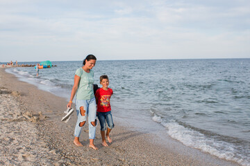 boy and mother walking along the sea beach