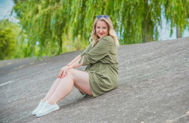 Happy woman of plus size, walks in the city enjoying life. Young lady with excess weight, stylishly dressed at the city park .Natural beauty