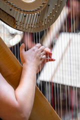 harp on symphony orchestra stage, detail of hands with strings