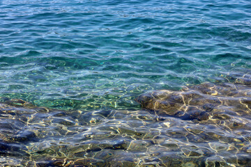 Obraz premium Transparent sea surface with stones on a bottom. Turquoise water for background