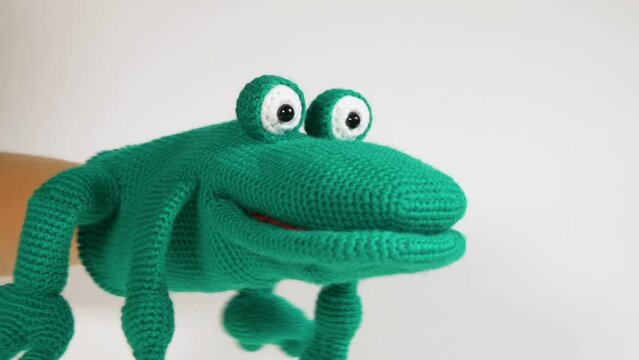 Knitted toy glove toad on a white background, a toy for the puppet theater. Close-up.