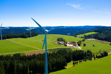 Aerial view of wind power plant in the bright green meadow and fir trees. St. Peter, Black forest,...