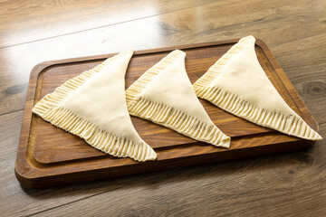 puff pastry triangles with minced meat on a wooden background. food concept