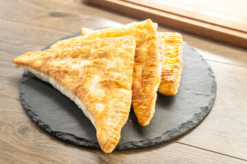 puff pastry triangles with minced meat on a wooden background. food concept