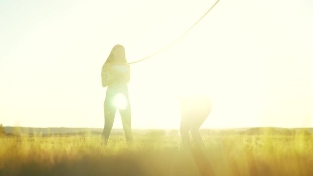 children in the park playing rope jumping. happy family kid dream concept. little girl jumping over a big jump rope joint play children silhouette outdoors lifestyle in the park