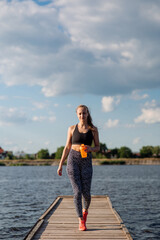 Sporty sexy woman in sportswear on the pier on hte water background