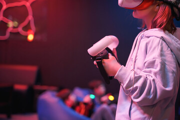 Girl playing vr game in 3d glasses headset. Virtual reality simulation club for gamers.Joysticks for futuristic video shooting game in hands.Innovation technology.Fun entertainment in neon light room