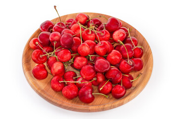 Red sweet cherries on stems on the wooden dish