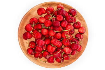 Red sweet cherries on stems on wooden dish, top view