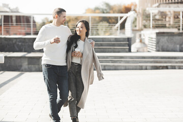 Young pretty couple walking on city background. Woman and man together having fun on urban background. Lovely young people dating.