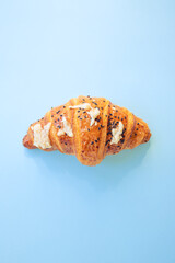 croissant with cheese and sesame seeds on blue background. Closeup, copy space, bakery, top view