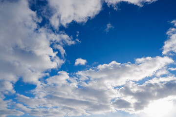 Sky with clouds and sun. White colour clouds against blue sky