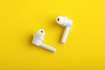 Technology concept : wireless headphone or ear bud on yellow background.