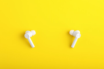 Technology concept : wireless headphone or ear bud on yellow background.