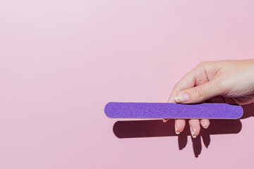 female hand filing nails polish on pink background. Concept of lady painting, polishing nails. Nail...