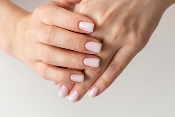 Female hands with beautiful nails with stylish trendy nude manicure.
